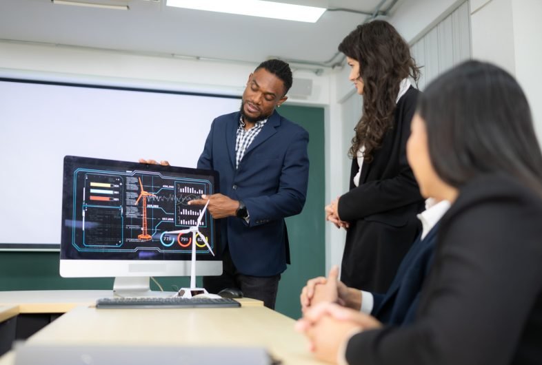 Diverse team of businessmen and engineers consultation on the engineering of a wind turbine that converts wind energy to electricity in the office.